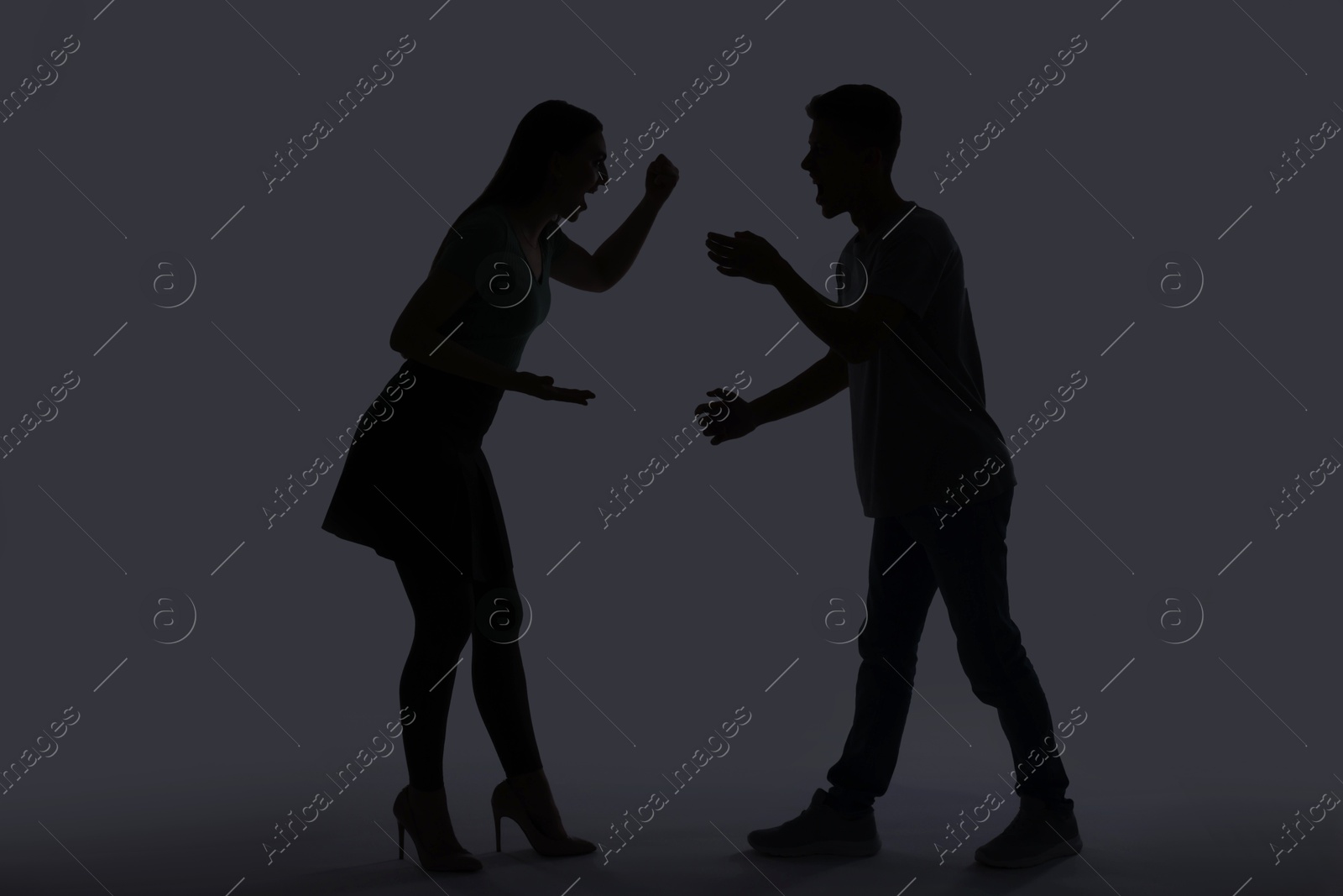 Photo of Domestic violence. Silhouette of couple quarreling on grey background