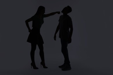 Photo of Domestic violence. Silhouette of woman punching her husband on grey background