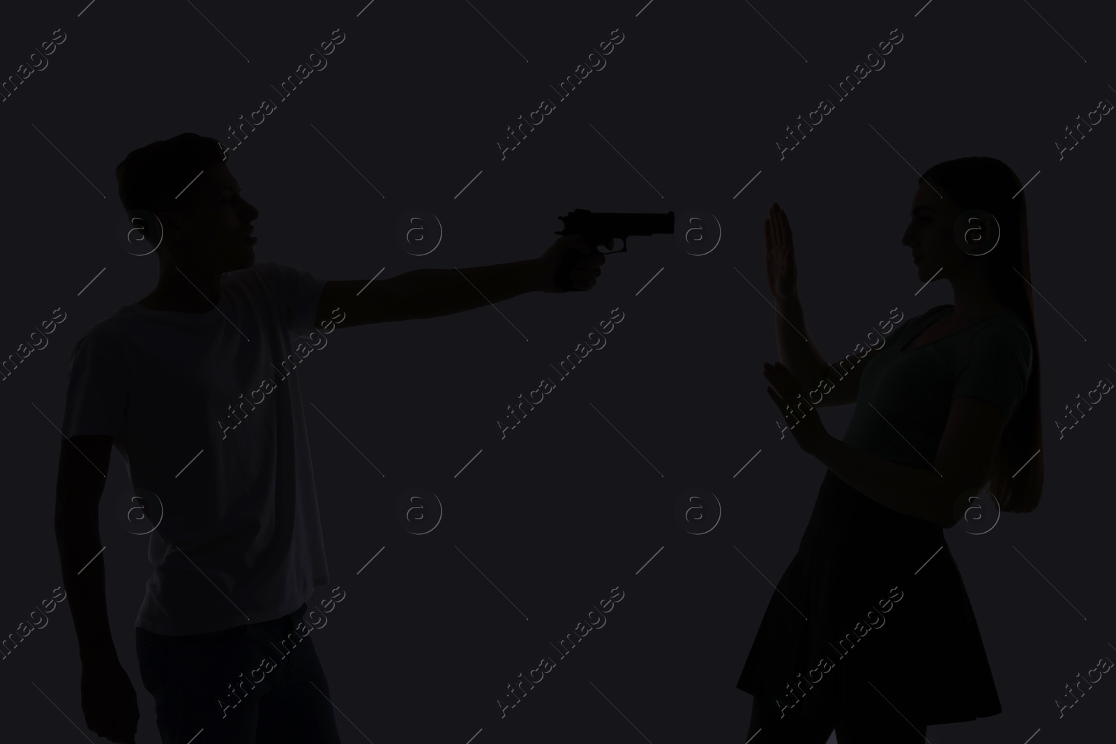 Photo of Domestic violence. Silhouette of man with gun threatening his wife on grey background