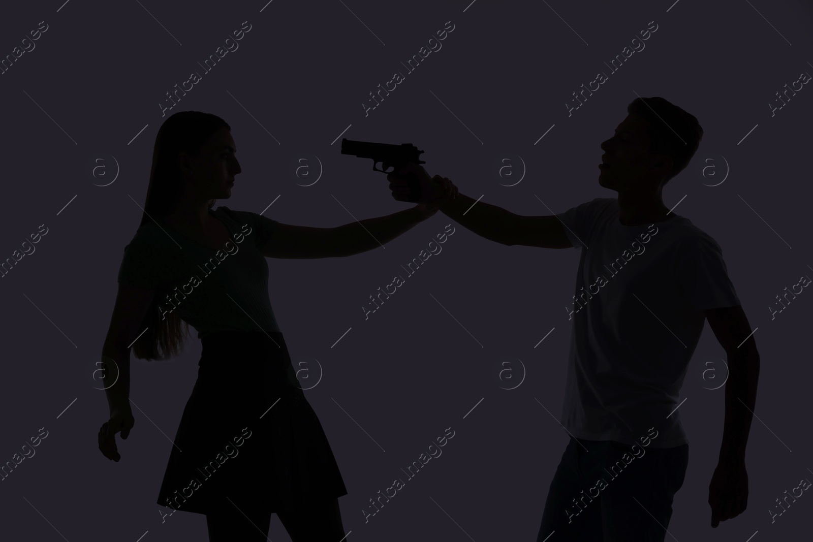 Photo of Domestic violence. Silhouette of man with gun threatening his wife on grey background