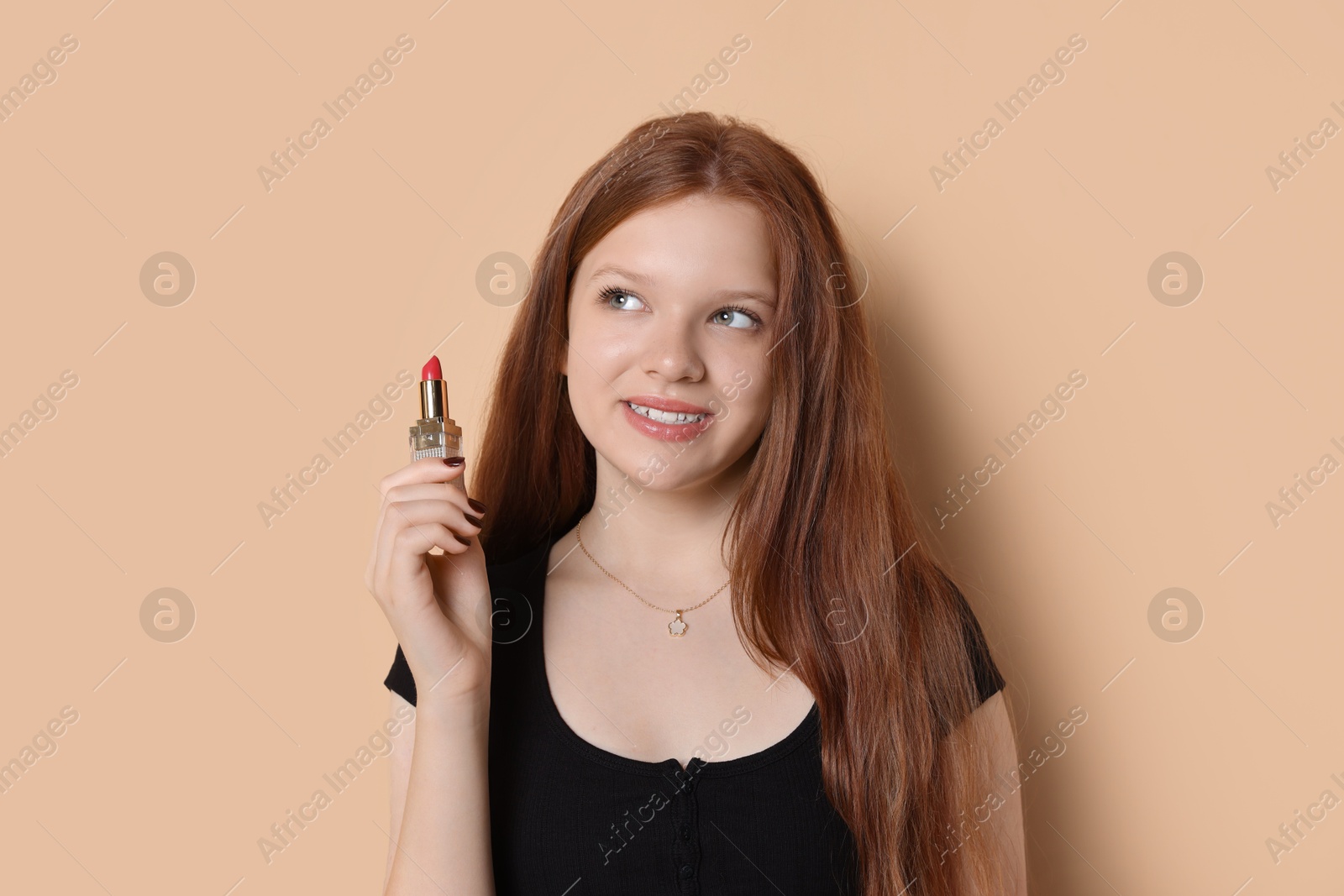 Photo of Smiling teenage girl with lipstick on beige background