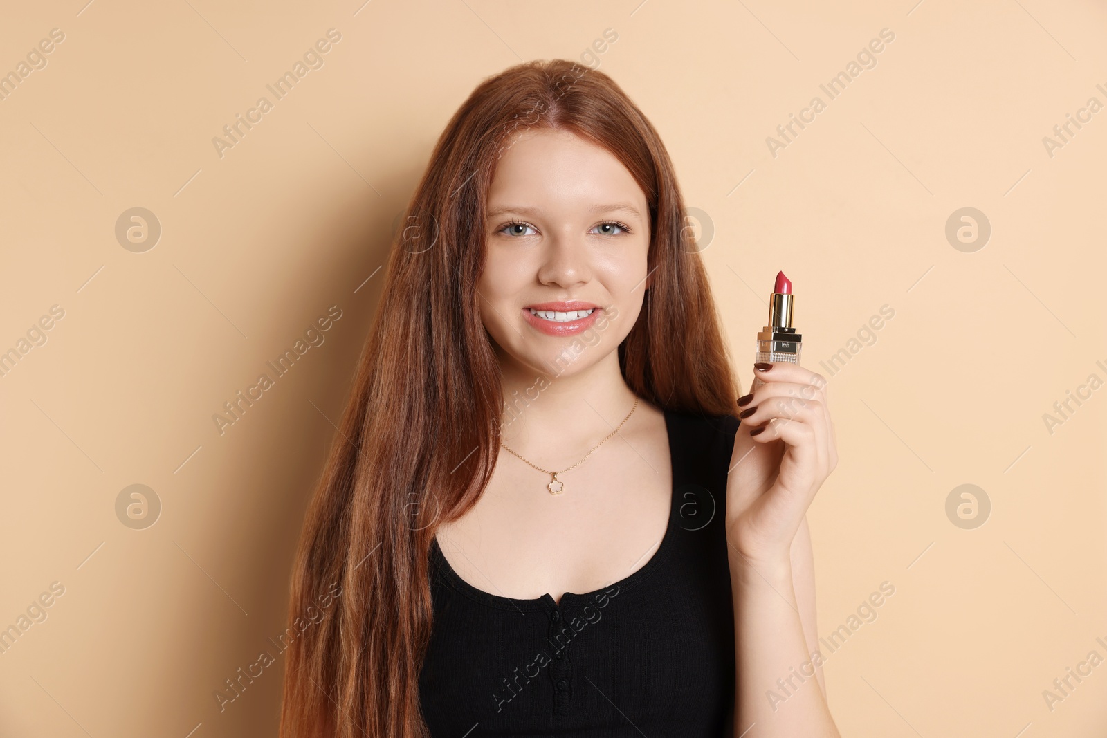 Photo of Smiling teenage girl with lipstick on beige background