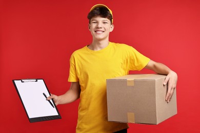 Photo of Teenage boy with parcel and clipboard working as courier on red background