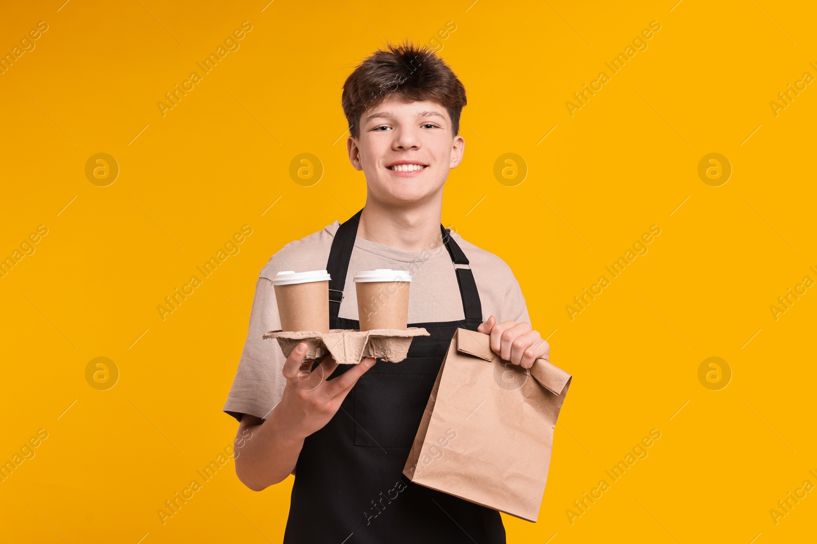 Photo of Teenage boy with order working as cashier on orange background