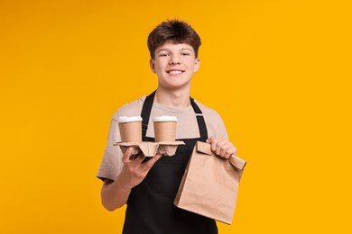 Photo of Teenage boy with order working as cashier on orange background