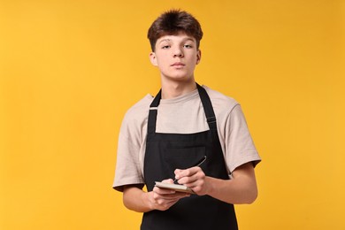 Photo of Boy with notepad taking order in cafe. Work for teenagers