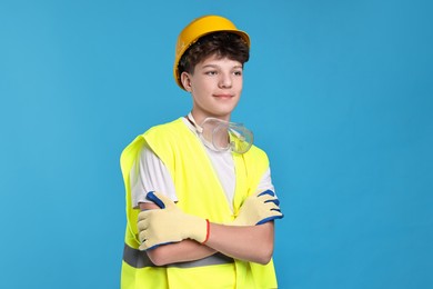 Photo of Teenage boy in hardhat and safety vest working as builder on blue background