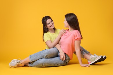 Photo of Portrait of happy twin sisters on orange background