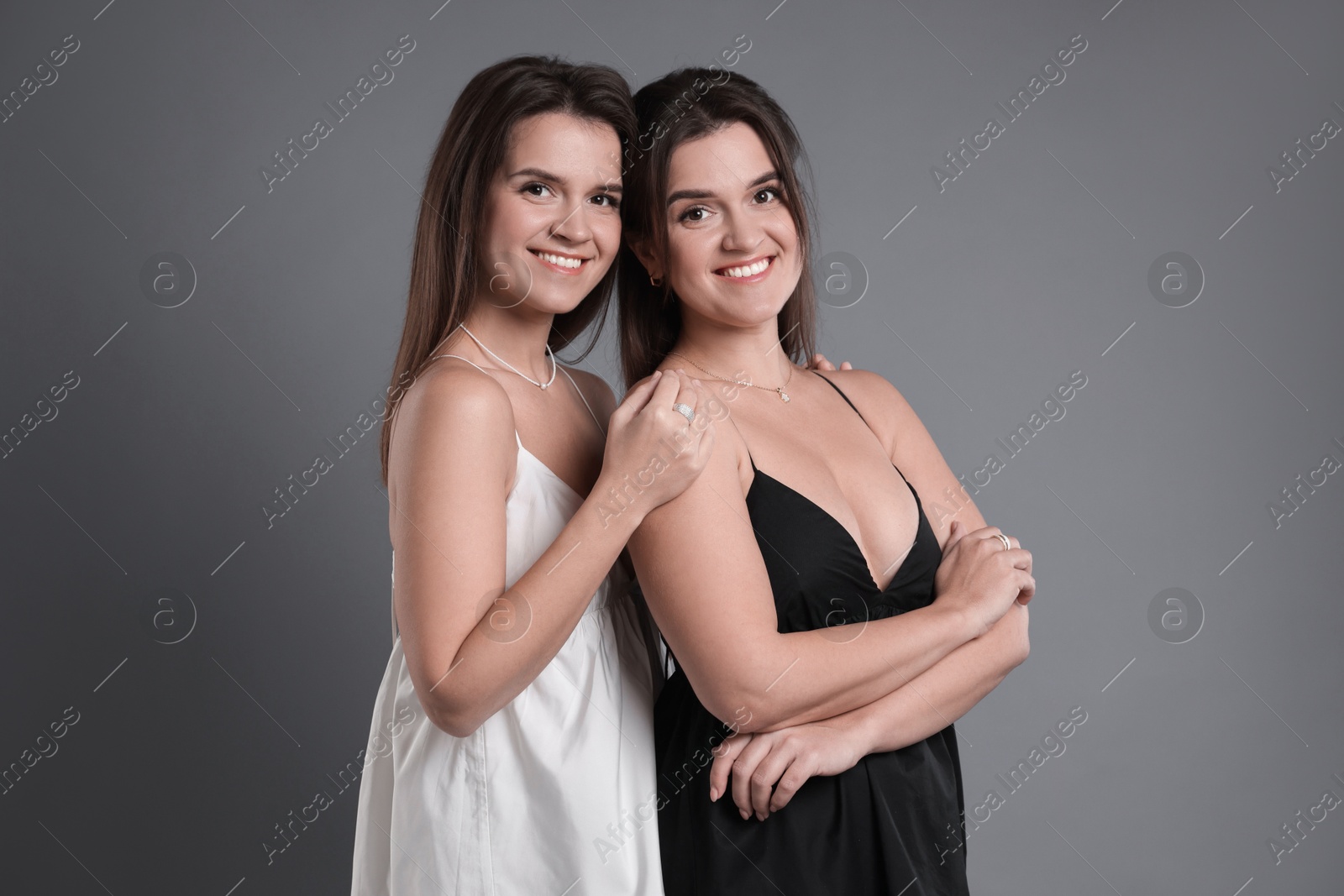 Photo of Portrait of beautiful twin sisters on grey background