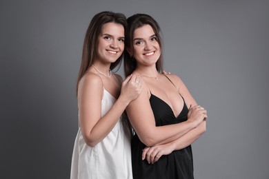 Photo of Portrait of beautiful twin sisters on grey background