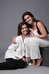 Portrait of beautiful twin sisters on grey background