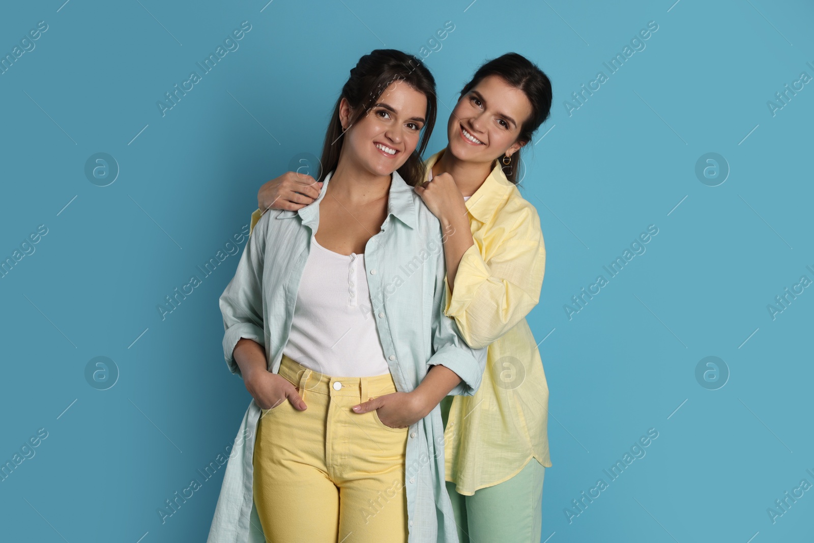 Photo of Portrait of beautiful twin sisters on light blue background