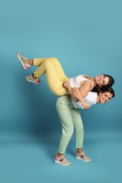 Beautiful twin sisters having fun on light blue background