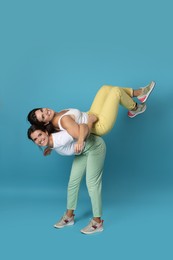 Beautiful twin sisters having fun on light blue background