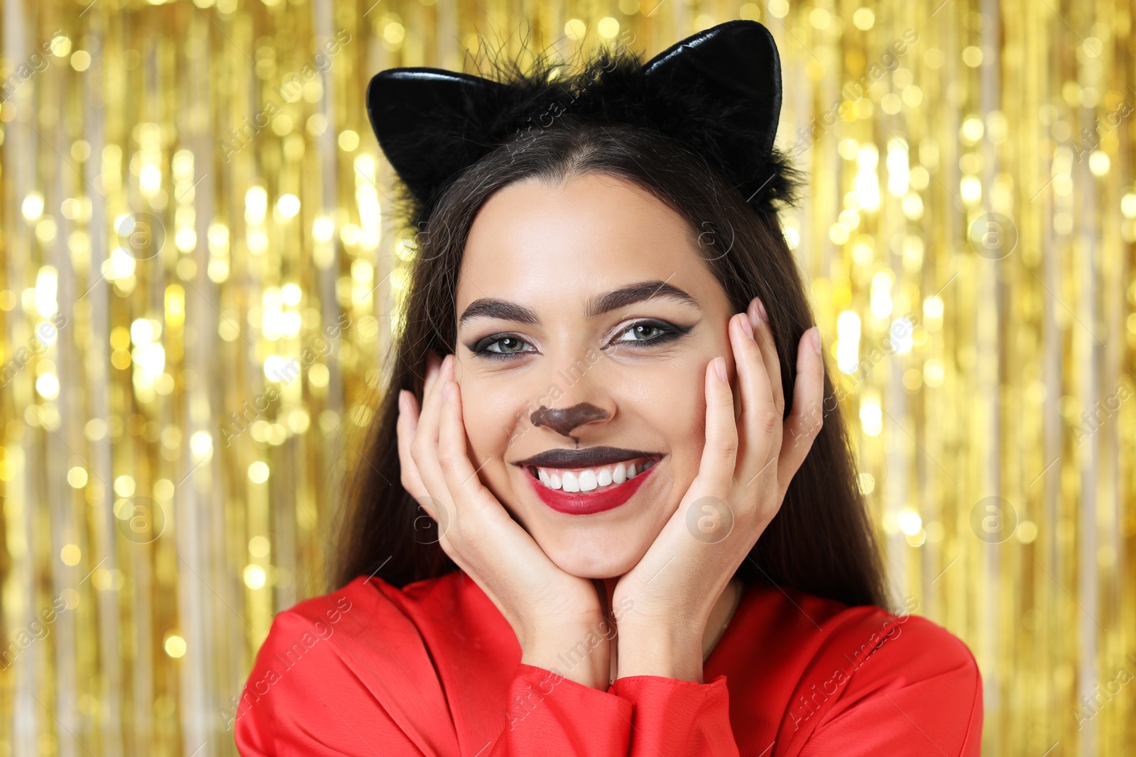 Photo of Beautiful woman with cat makeup and ears on golden background