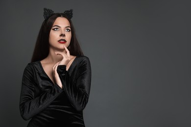 Photo of Attractive woman with cat makeup and ears on grey background. Space for text