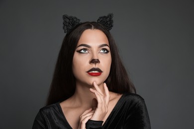 Photo of Attractive woman with cat makeup and ears on grey background