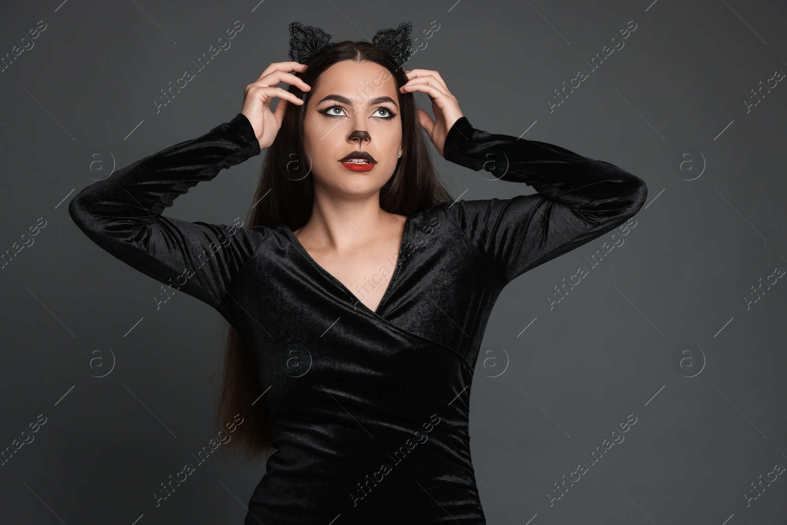 Photo of Attractive woman with cat makeup and ears on grey background