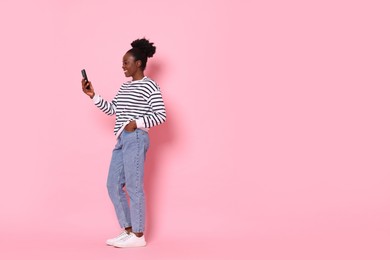 Photo of Happy woman with smartphone on pink background. Space for text