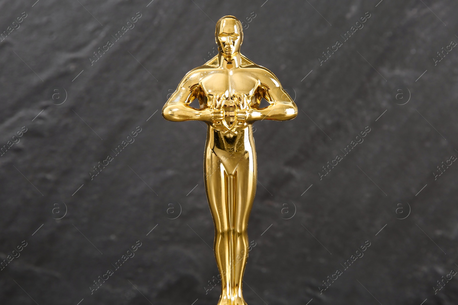 Photo of Golden trophy in shape of human figure against blurred gray background