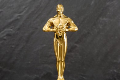 Photo of Golden trophy in shape of human figure against blurred gray background