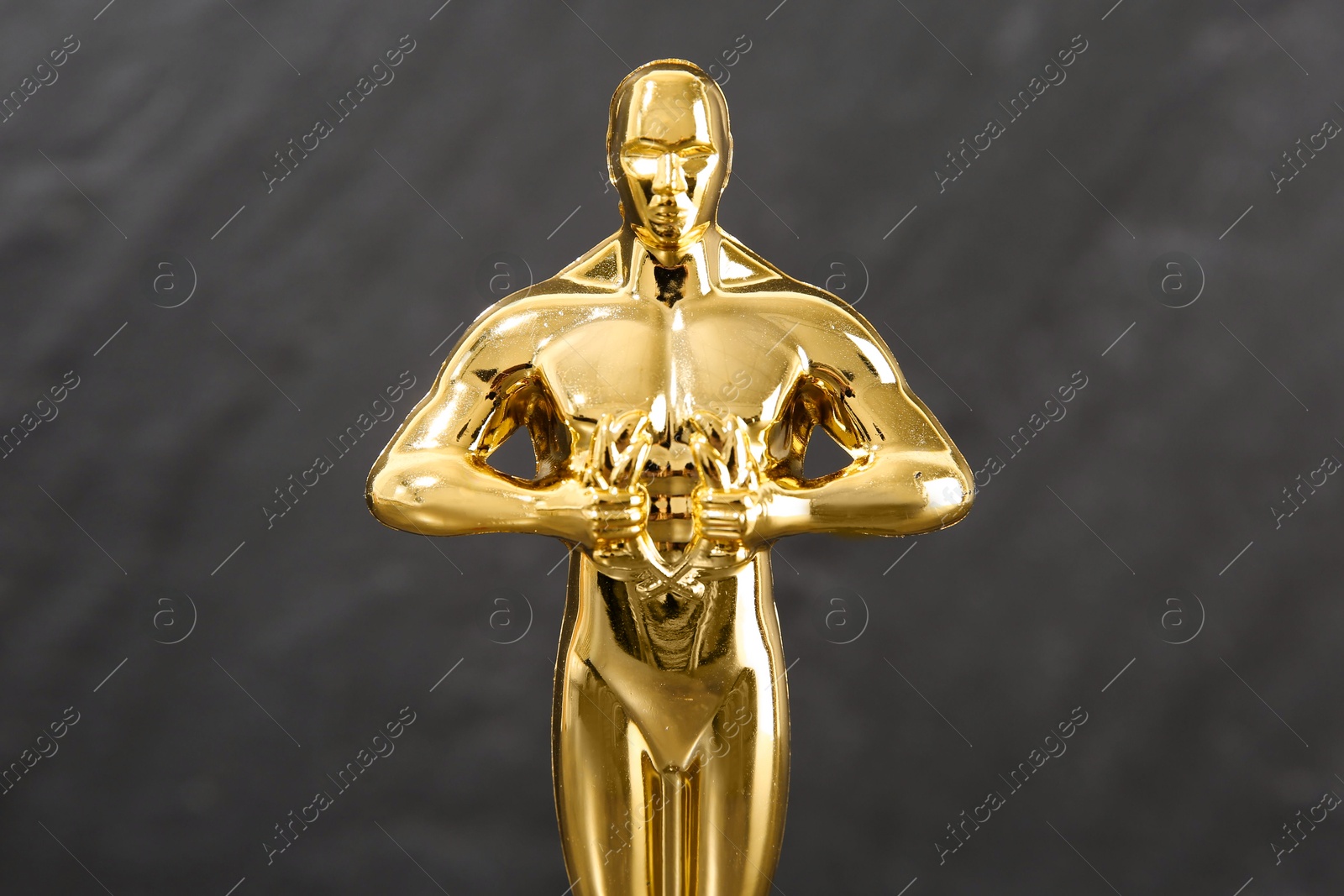 Photo of Golden trophy in shape of human figure against blurred gray background