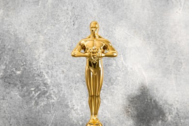 Photo of Golden trophy in shape of human figure against blurred gray background