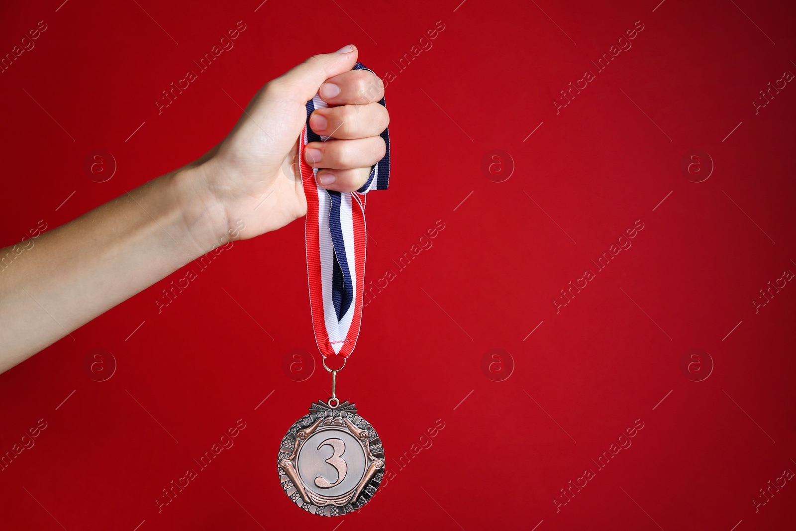 Photo of Woman with bronze medal on red background, closeup. Space for text