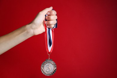 Photo of Woman with bronze medal on red background, closeup. Space for text