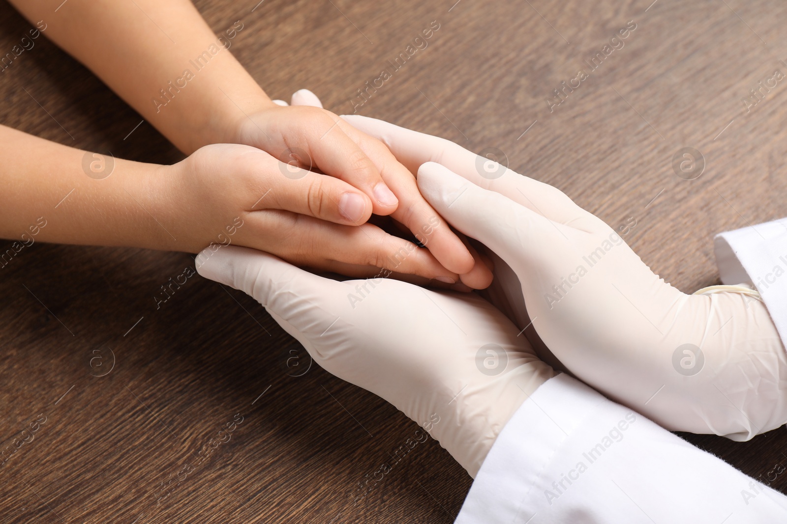 Photo of Doctor and child at wooden table, closeup