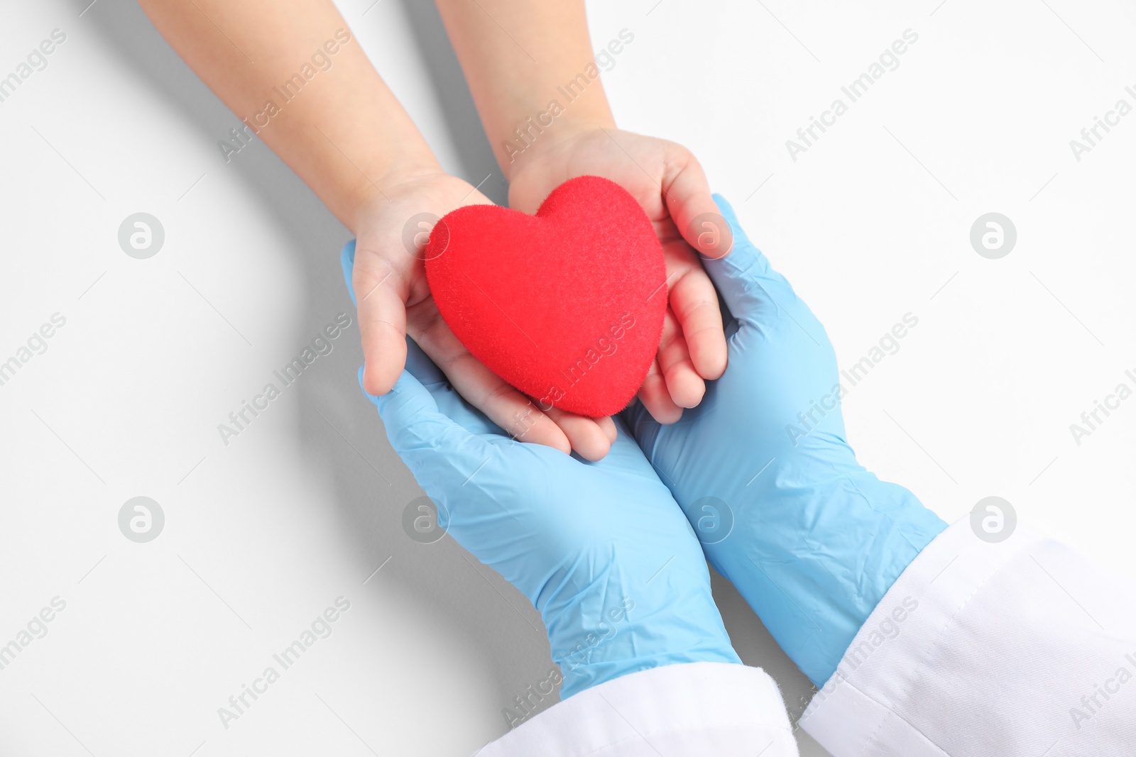 Photo of Doctor and child holding heart model on white background, top view