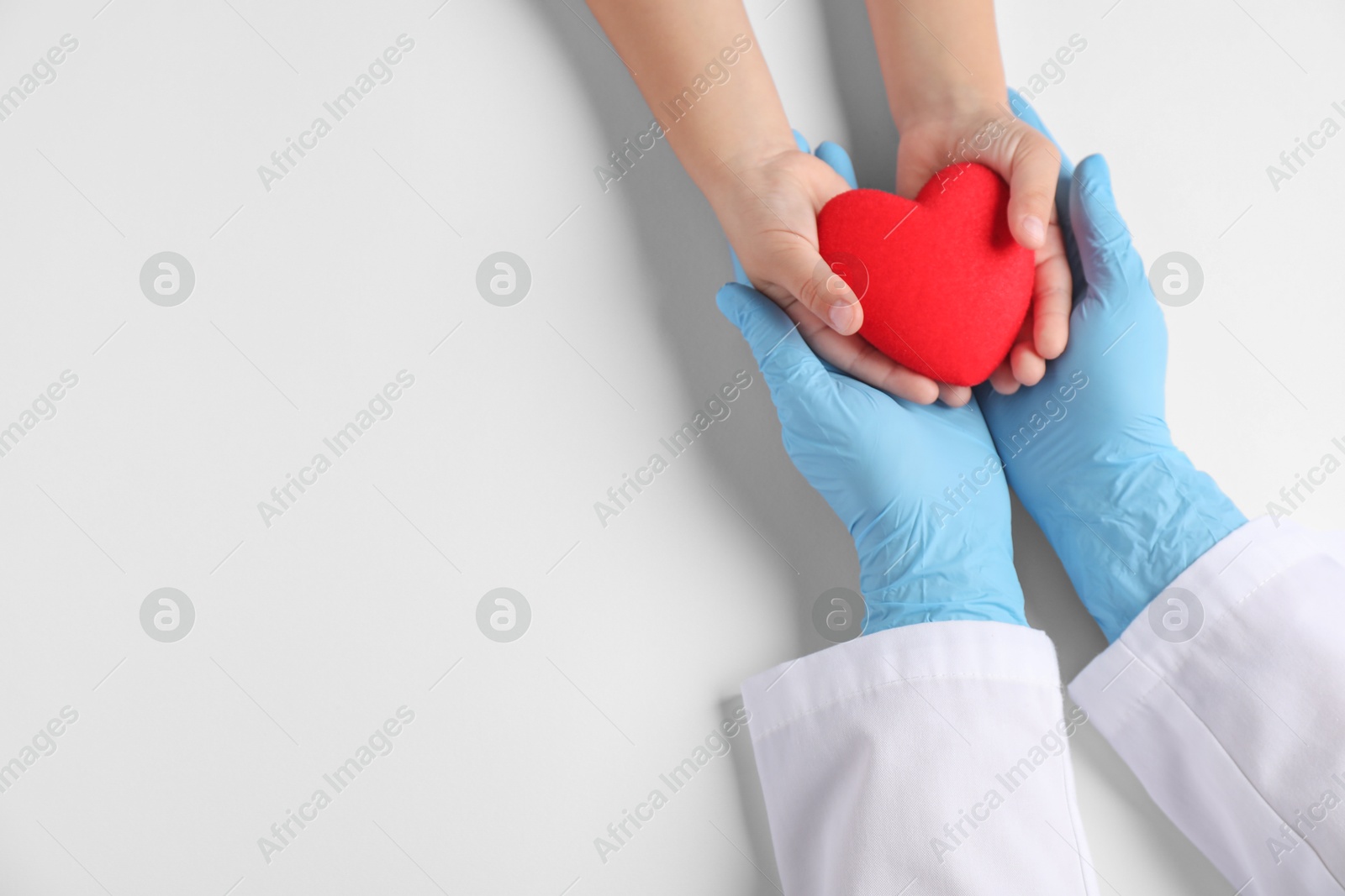 Photo of Doctor and child holding heart model on white background, top view. Space for text