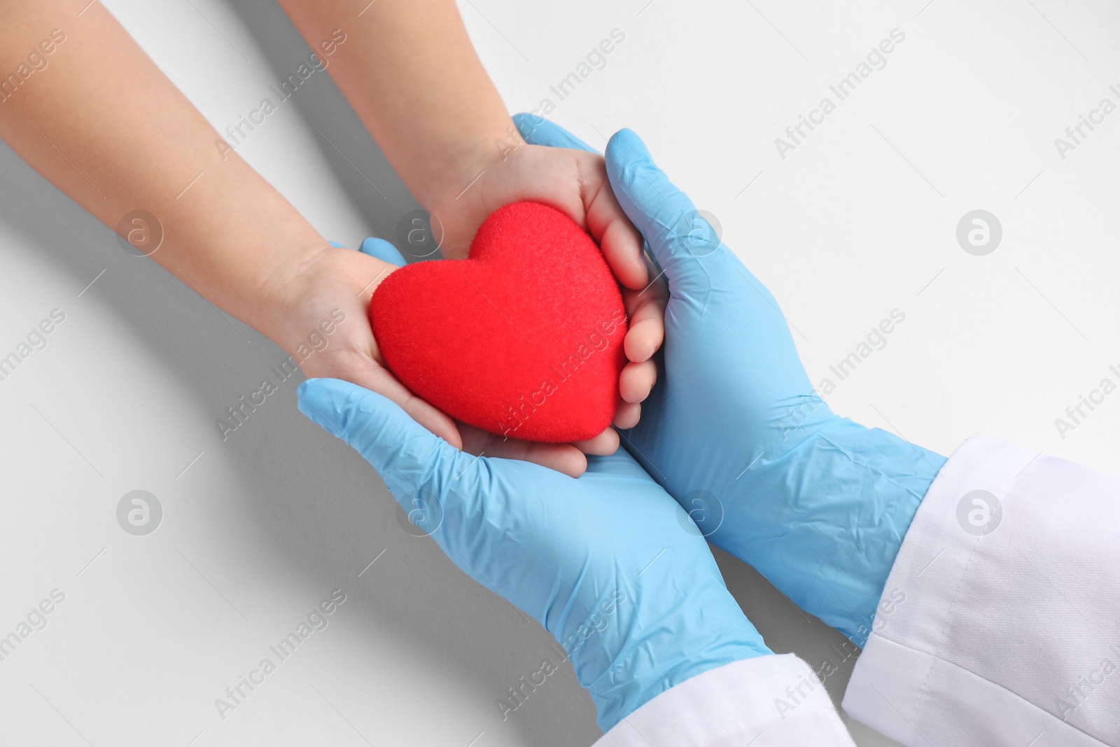 Photo of Doctor and child holding heart model on white background, top view