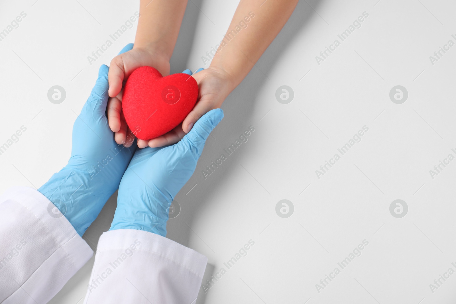 Photo of Doctor and child holding heart model on white background, top view. Space for text