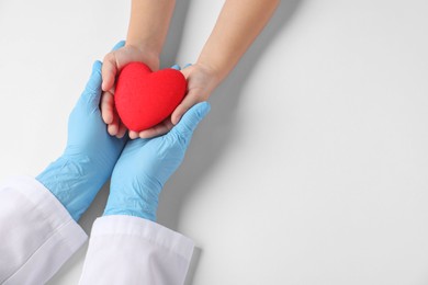 Photo of Doctor and child holding heart model on white background, top view. Space for text