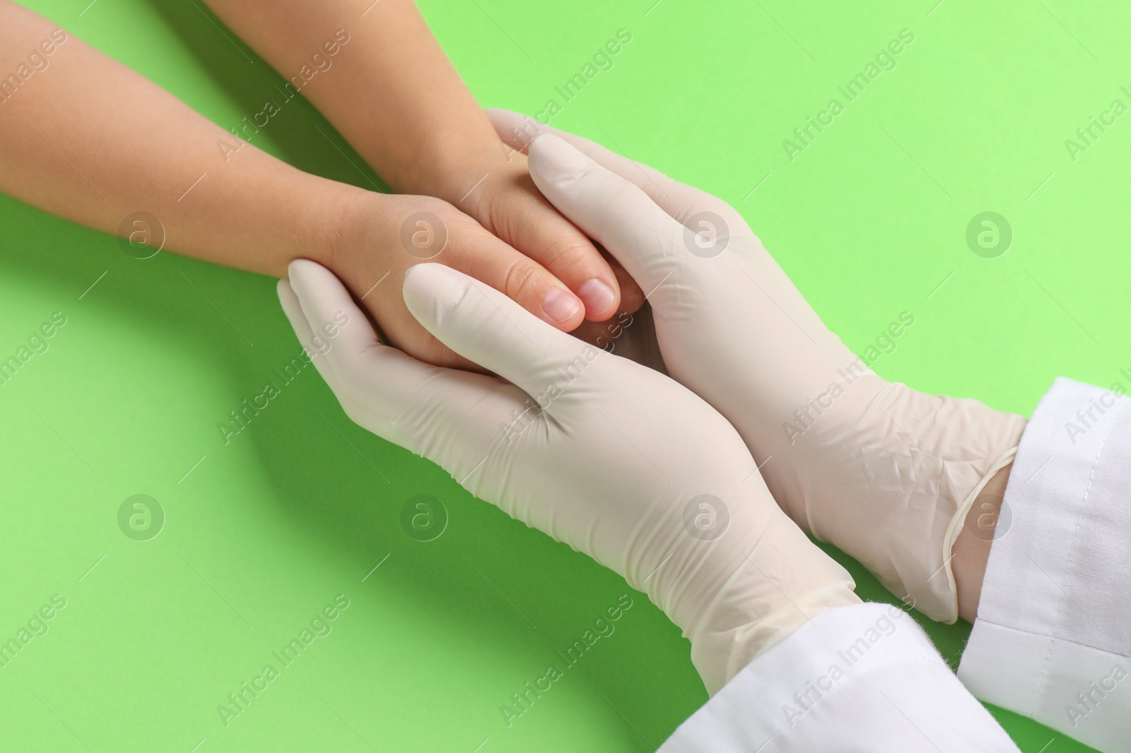 Photo of Doctor and child on light green background, closeup