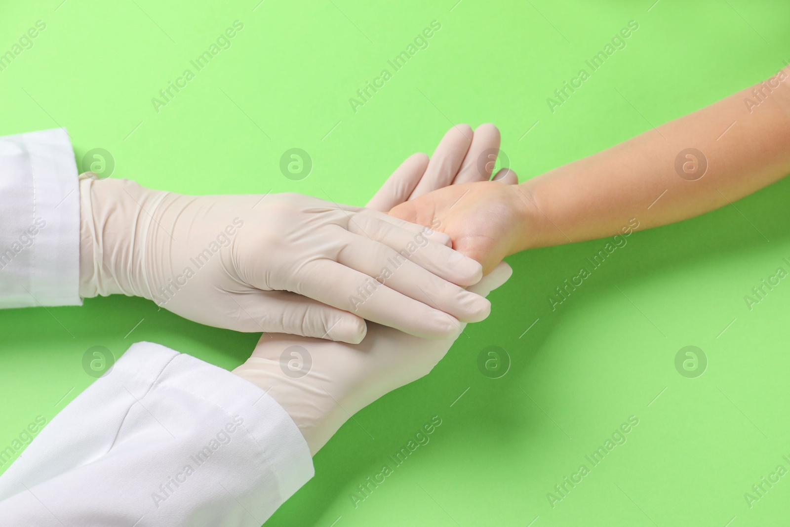 Photo of Doctor and child on light green background, closeup