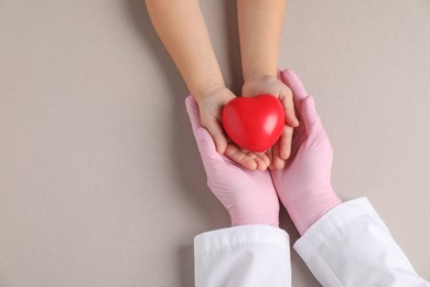 Photo of Doctor and child holding heart model on light grey background, top view. Space for text