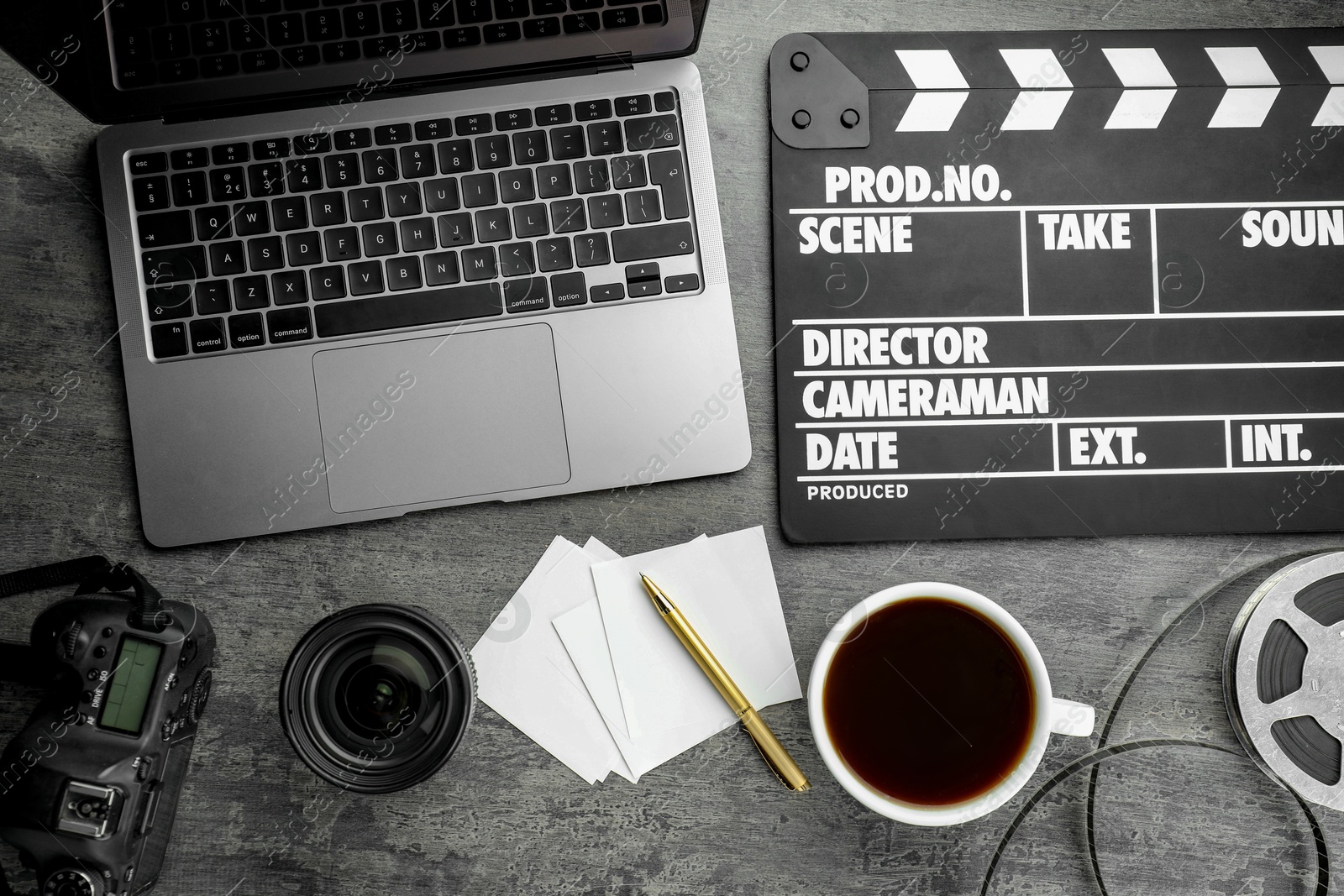 Photo of Flat lay composition with movie clapper, film reel and camera lens on grey textured table