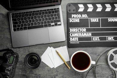 Photo of Flat lay composition with movie clapper, film reel and camera lens on grey textured table