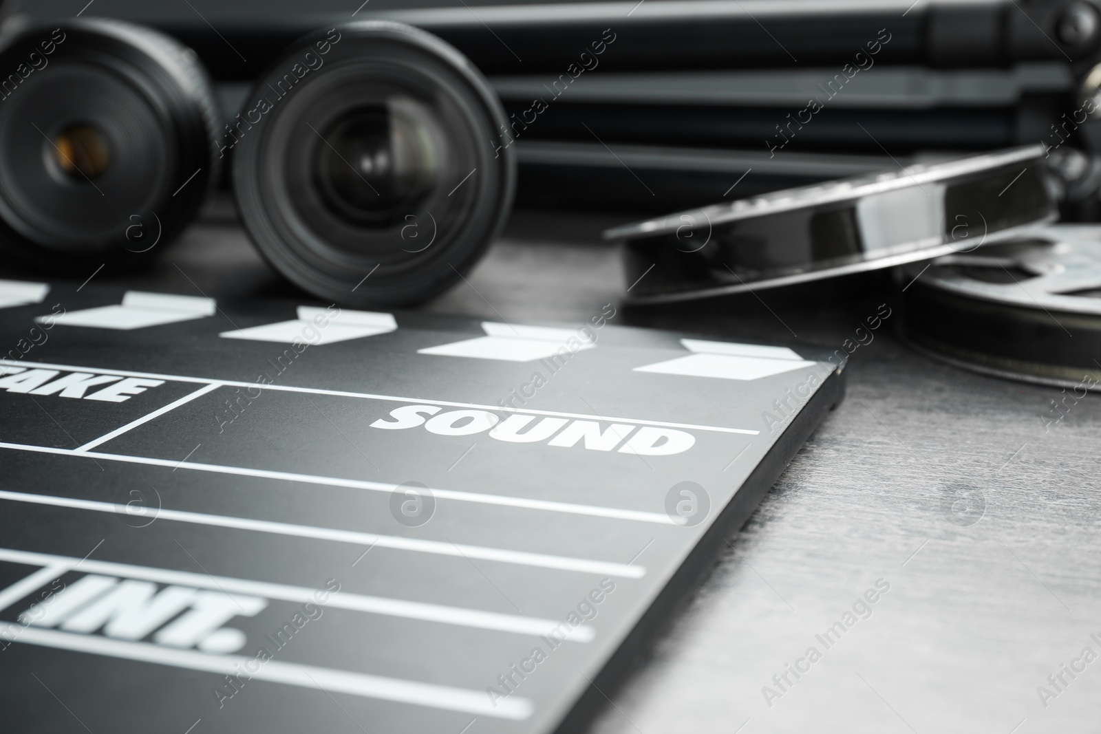 Photo of Movie clapper, film reels and camera lens on table, closeup