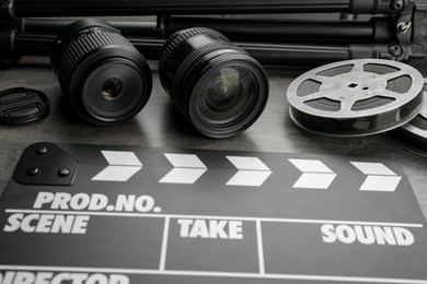 Photo of Movie clapper, film reels and camera lens on grey table, closeup