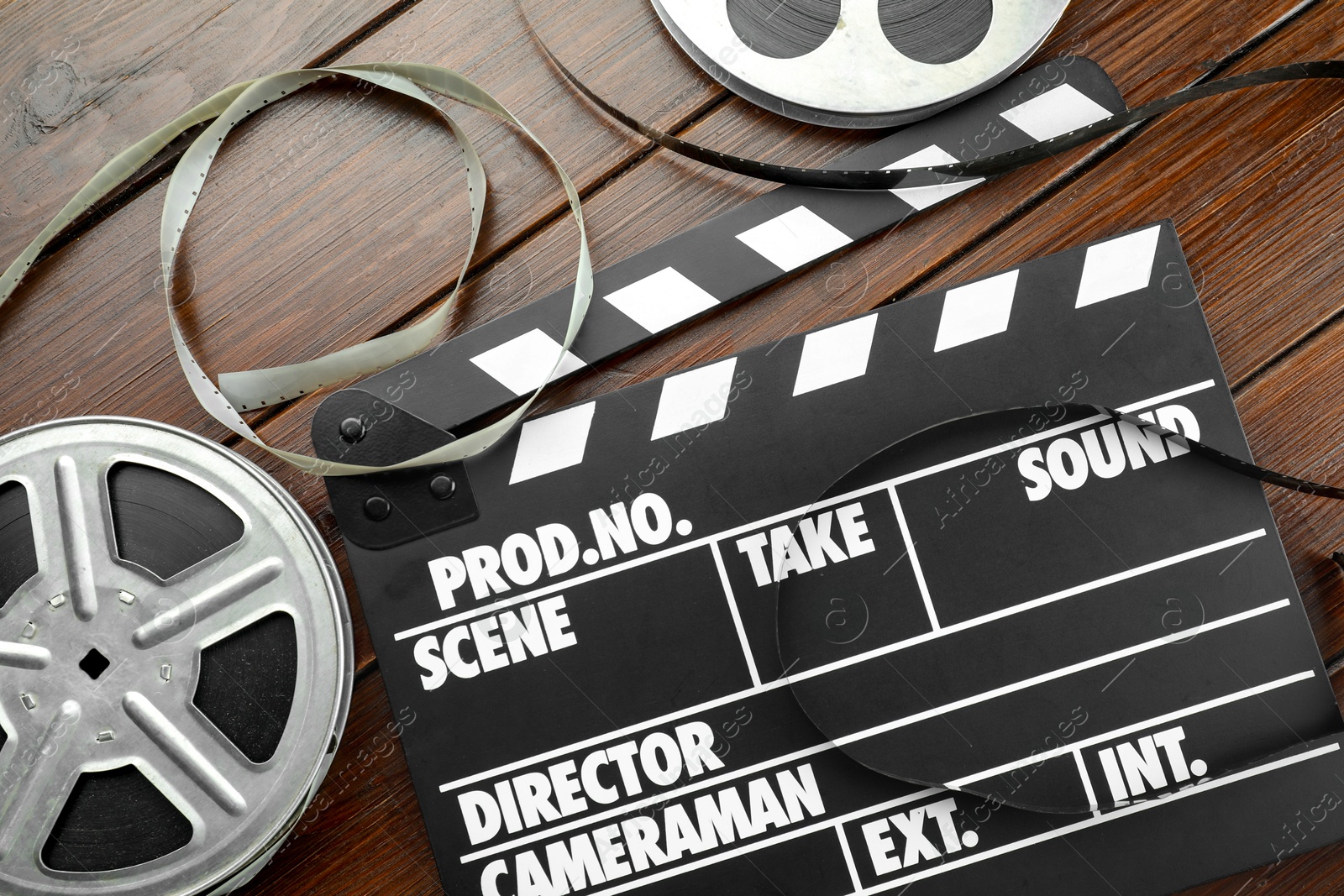 Photo of Movie clapper and film reels on wooden table, flat lay