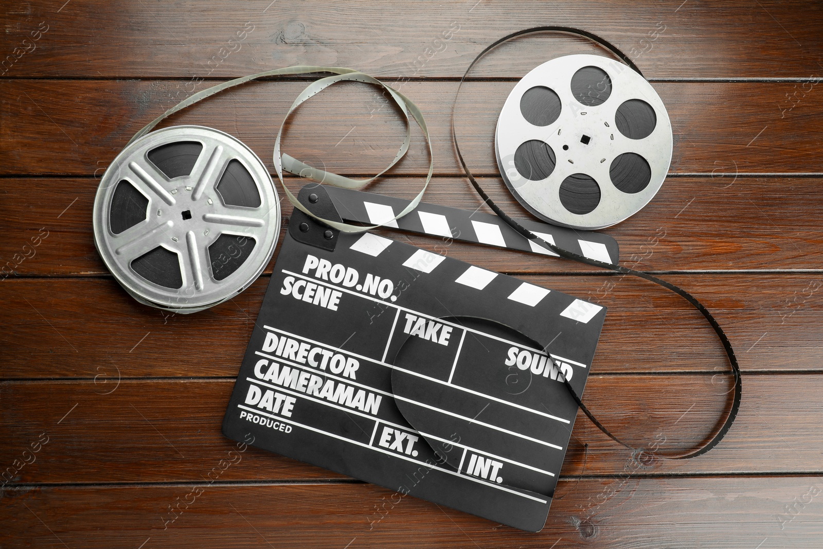 Photo of Movie clapper and film reels on wooden table, flat lay