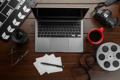 Photo of Flat lay composition with movie clapper, film reel, camera and laptop on wooden table