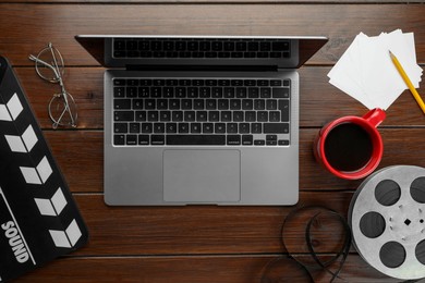 Photo of Flat lay composition with movie clapper, film reel and laptop on wooden table