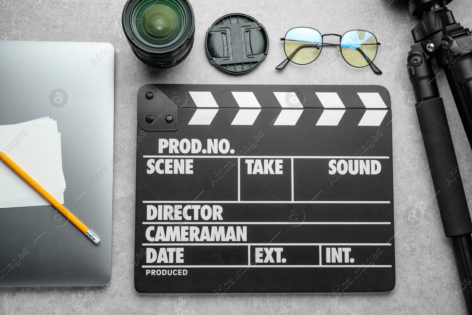 Photo of Flat lay composition with movie clapper, camera lens and laptop on grey textured table