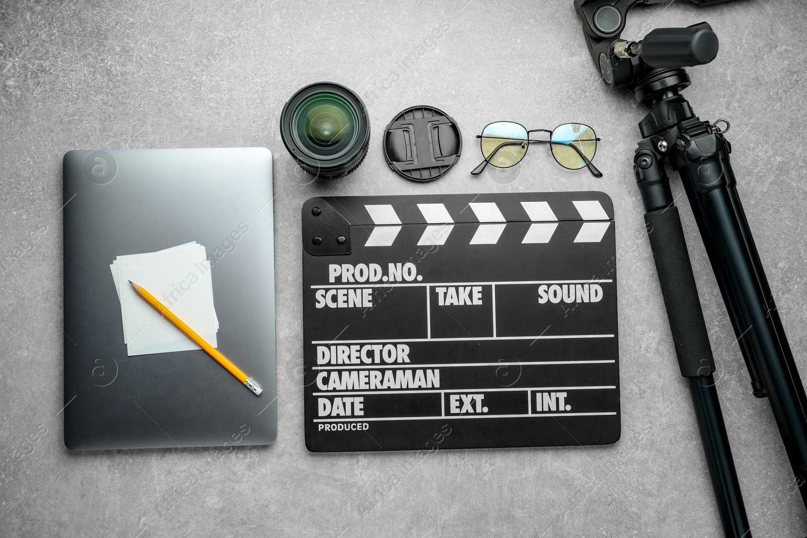 Photo of Flat lay composition with movie clapper, camera lens and laptop on grey textured table