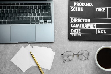 Photo of Flat lay composition with movie clapper and laptop on grey textured table