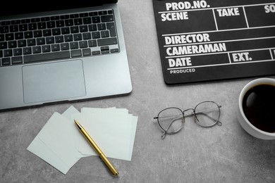 Photo of Flat lay composition with movie clapper and laptop on grey textured table